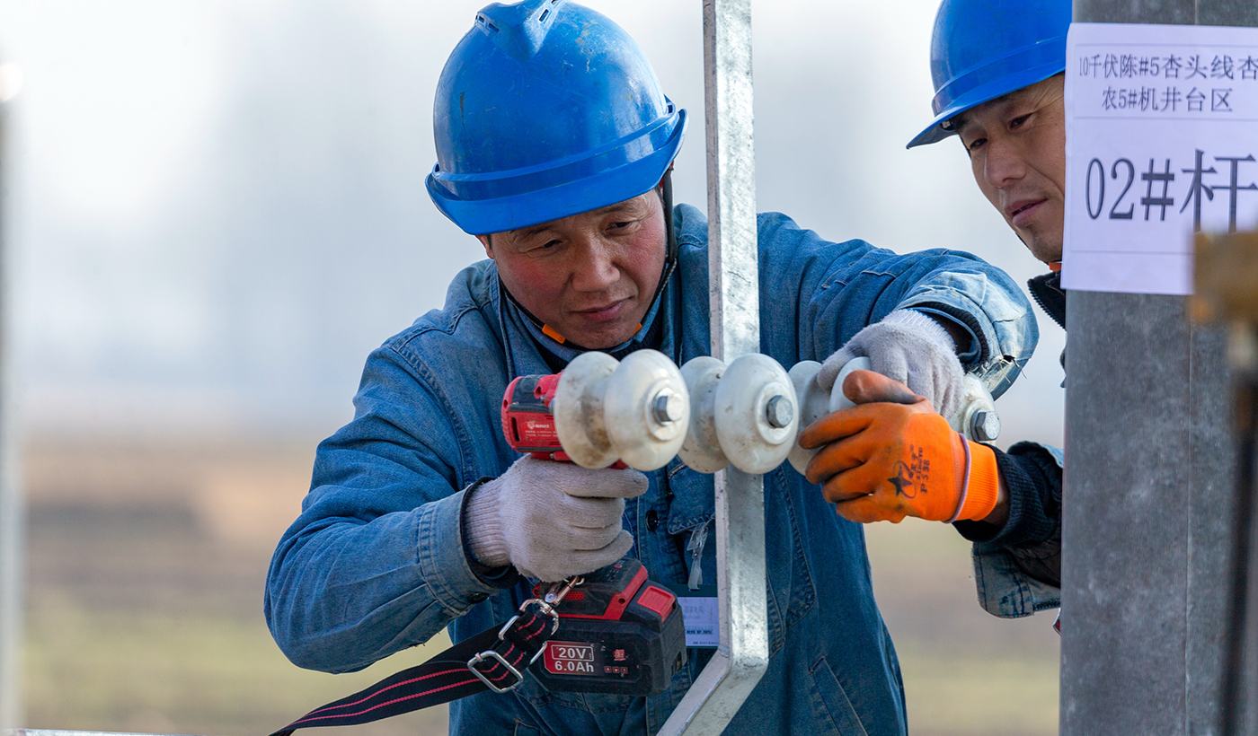 整个施工过程严格遵循安全规范与技术要求，确保每一环节精准到位。图4为，2026年1月8日上午，在河南省安阳市滑县半坡店镇杏头村的农田里，杏头5号机井通电配套工程施工现场，国网滑县供电公司施工队员魏成亮正在安装变压器绝缘子。（王亚方 摄）
