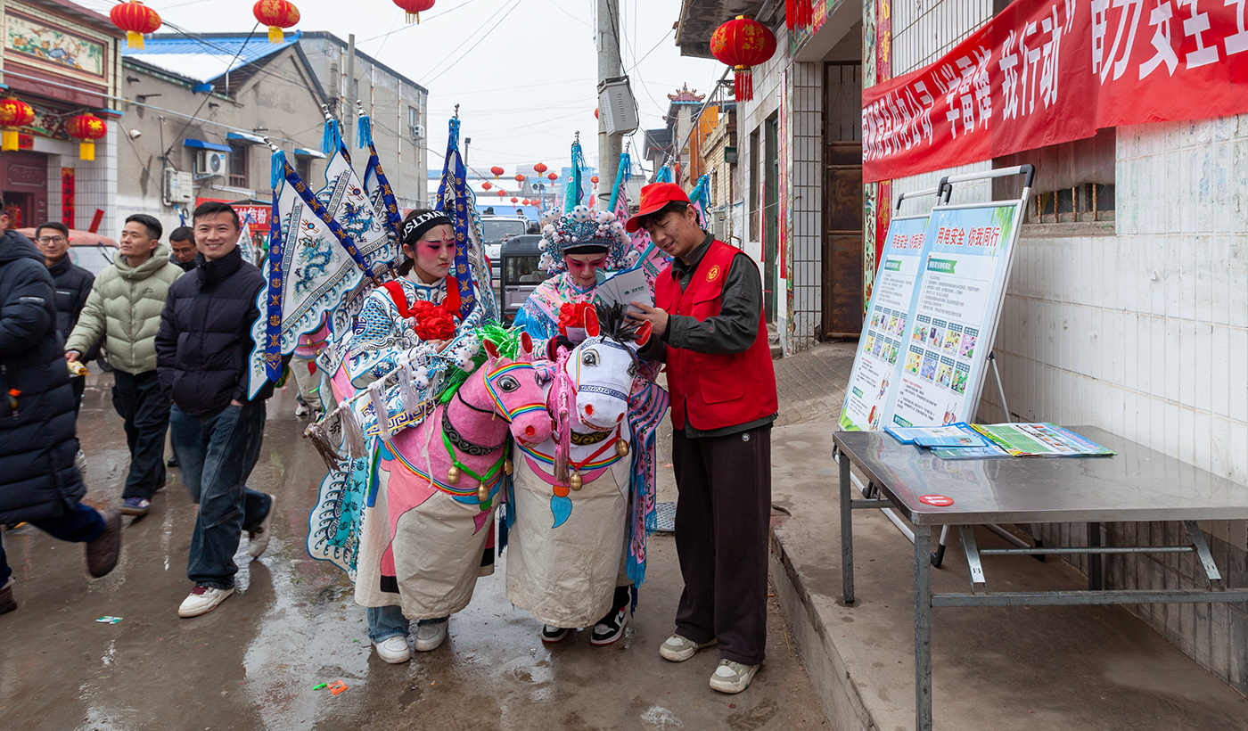 图为，2026年3月3日（农历正月十五）上午，正值元宵佳节，滑县城关街道孙王庄村社火表演如火如荼，村内锣鼓喧天、人声鼎沸，国网滑县供电公司组织志愿服务队走进该村，开展“学雷锋 我行动”电力安全进庙会活动。（王亚方 摄）