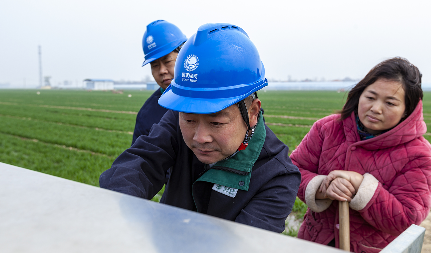 “一个电话，电工比外卖来得还快！”康会民指着麦田里的汩汩水流说，“有他们守着，浇地心里踏实。”截至目前，服务队已巡视供电线路1520千米、变压器2160台，消除各类隐患65处。图为，2026年3月16日上午，国网滑县供电公司电力服务队队员康玉川、赵强在八里营镇东风村麦田，检查春灌用电设备并提醒村民安全用电。（王亚方 摄）